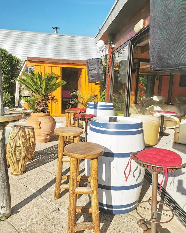 Le bar de la terrasse et ses tables en tonneaux