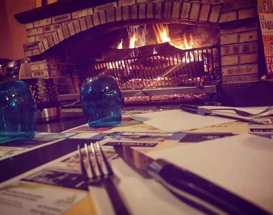 Le feu de bois du grill, allumé derrière une table dressée